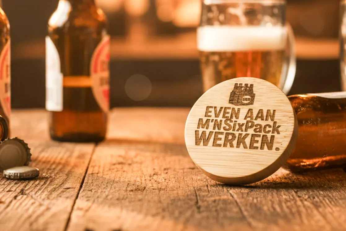 Ronde houten bieropener met gegraveerde tekst , gemaakt van bamboe met metalen onderzijde. Ambachtelijk gegraveerd door De Meesterbrander.