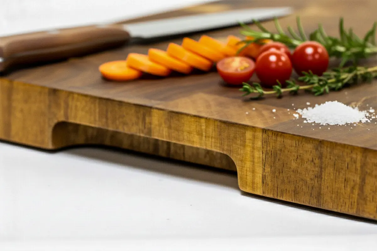 End-grain snijplank van acaciahout met handgreep. Warme houtnerf, ambachtelijke afwerking, subtiele zijgravure – gefotografeerd in Meesterbrander-stijl.