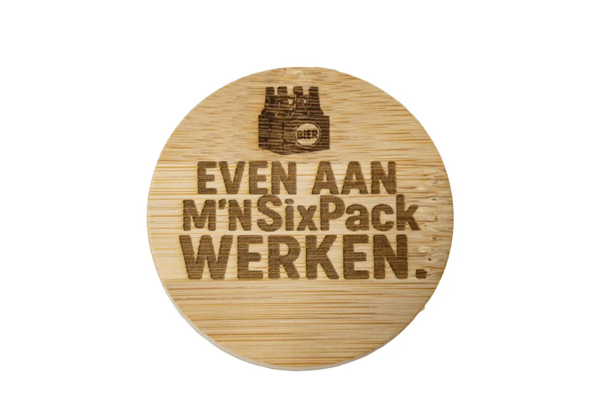 Ronde houten bieropener met gegraveerde tekst “Even aan mijn sixpack werken”, gemaakt van bamboe met metalen onderzijde. Ambachtelijk gegraveerd door De Meesterbrander.
