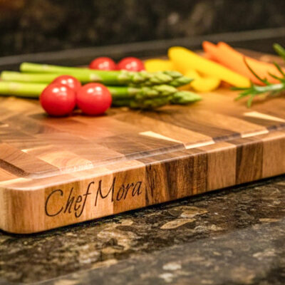 End-grain snijplank met handgreep en vochtgroef. Warme houtnerf, ambachtelijke afwerking, subtiele zijgravure – gefotografeerd in Meesterbrander-stijl.