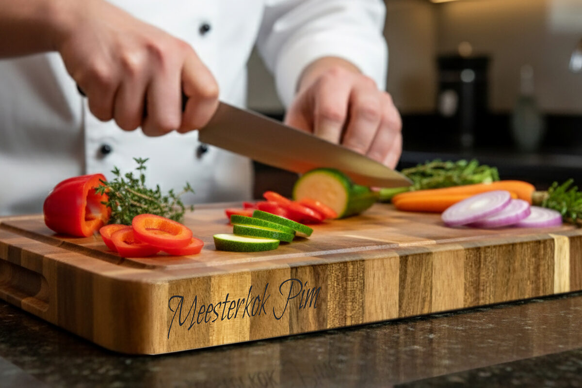 End-grain snijplank met handgreep en vochtgroef. Warme houtnerf, ambachtelijke afwerking, subtiele zijgravure – gefotografeerd in Meesterbrander-stijl.