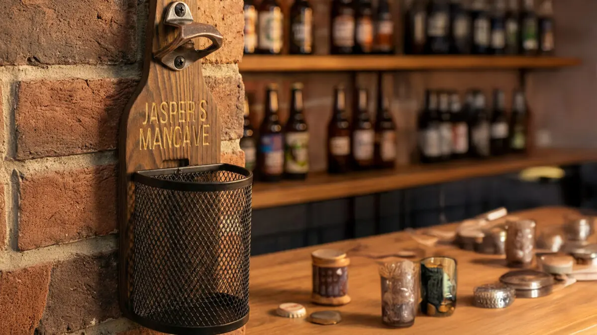 Houten Wandbieropener met Dopjesmandje Afneembaar metalen dopjesmandje gevuld met bierdopjes bij houten wandbieropener