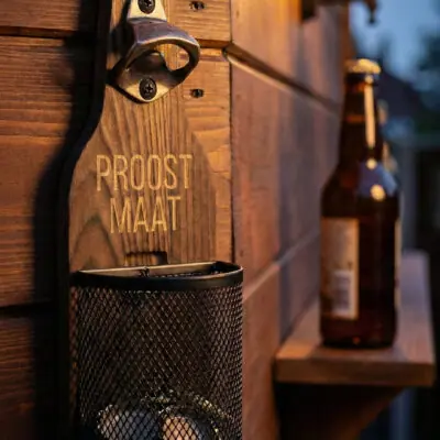 Houten Wandbieropener met Dopjesmandje Houten wandbieropener met dopjesmandje op veranda tijdens zomer en BBQ-seizoen