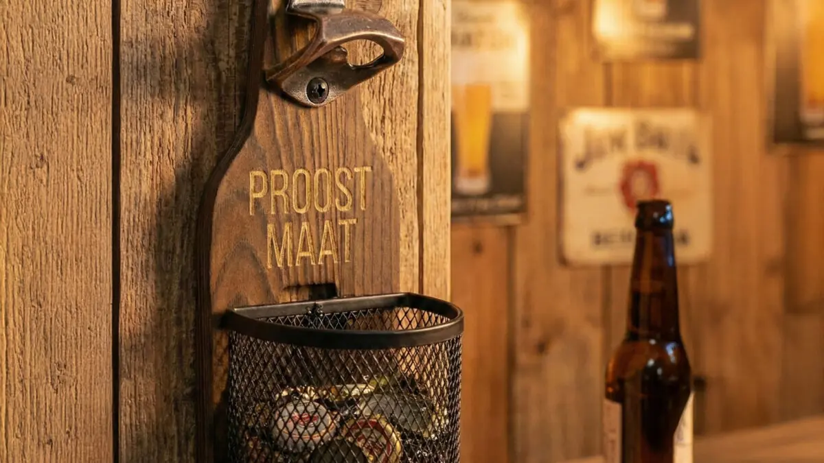 Houten Wandbieropener met Dopjesmandje Houten wandbieropener met dopjesmandje op veranda tijdens zomer en BBQ-seizoen