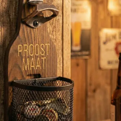 Houten Wandbieropener met Dopjesmandje Houten wandbieropener met dopjesmandje op veranda tijdens zomer en BBQ-seizoen