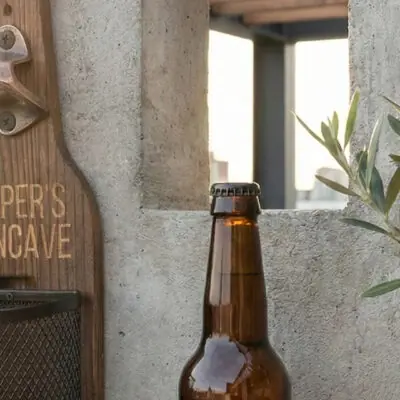 Houten Wandbieropener met Dopjesmandje Afneembaar metalen dopjesmandje gevuld met bierdopjes bij houten wandbieropener