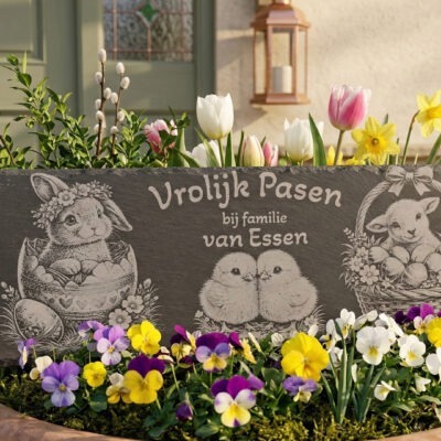 Luxe leisteen van 30x10 cm met paasafbeeldingen, decoratief geplaatst tussen blauwe druifjes en viooltjes.